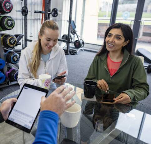 Two Women Speaking with Receptionist at Gym